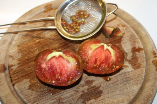 Augeschnittene dunkle Tomate mit Tomatensamen