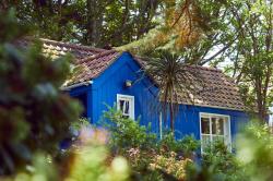 Blaues Holzhaus bzw. Schwedenhaus mit weissen Fenstern in der Natur.
