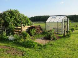 Gewächshaus und Komposthaufen im Garten